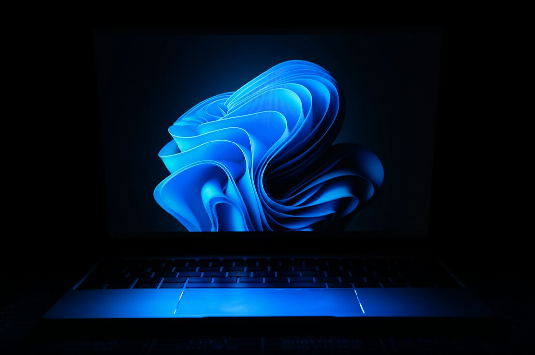 Laptop screen showing colorful programming code on a wooden desk